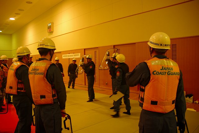 きい乗組員が基本的な楯の構え方を説明している様子