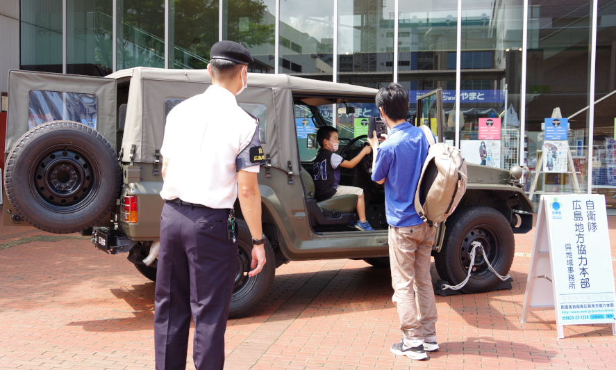 来場者の親子が陸上自衛隊の1/2tトラックにて記念撮影している様子