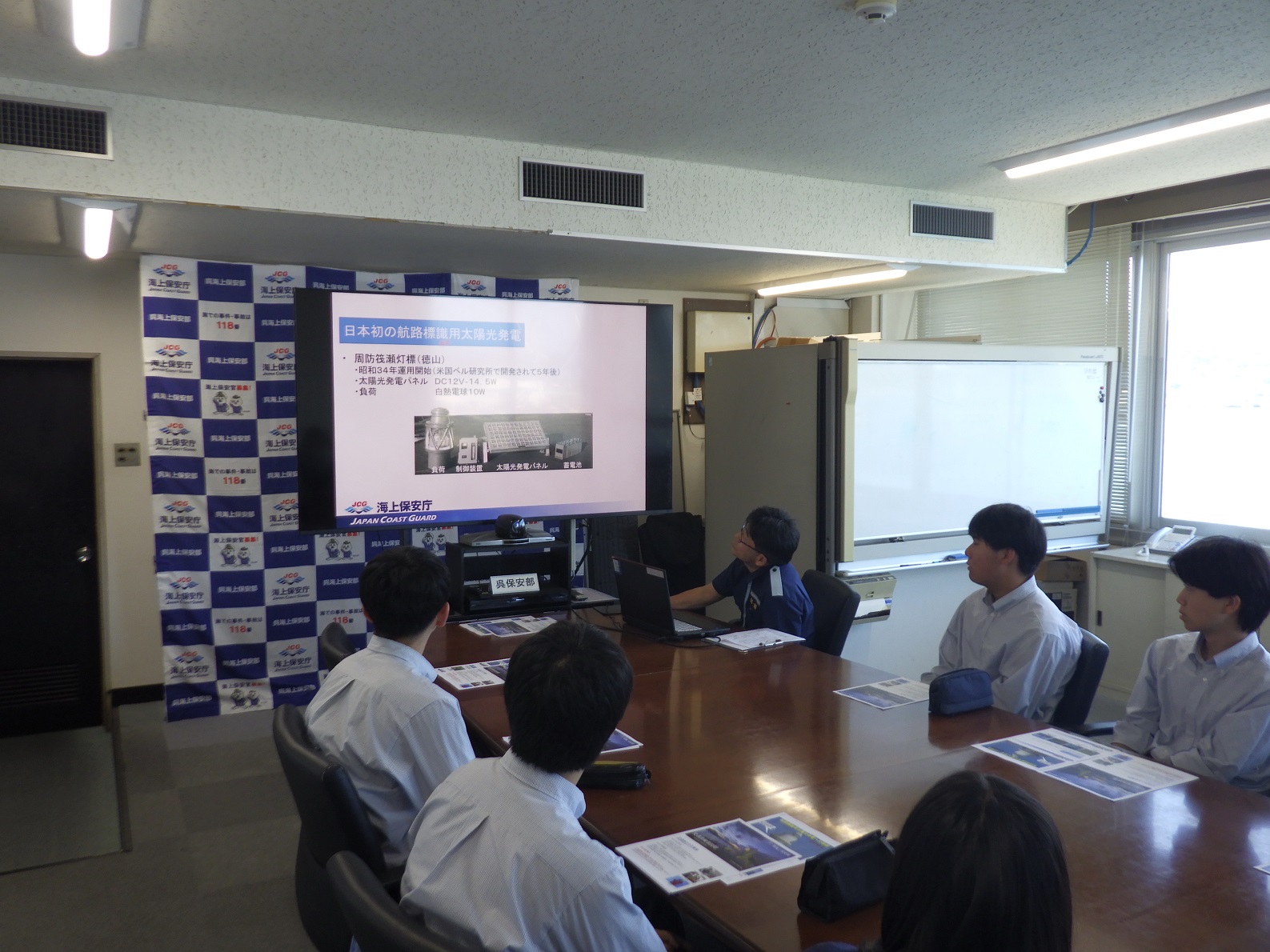 職員が高校生に対しクリーンエネルギーな灯台に関する説明を実施している様子