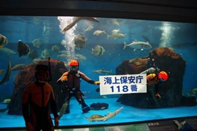 水槽内で118番の宣伝をする潜水士
