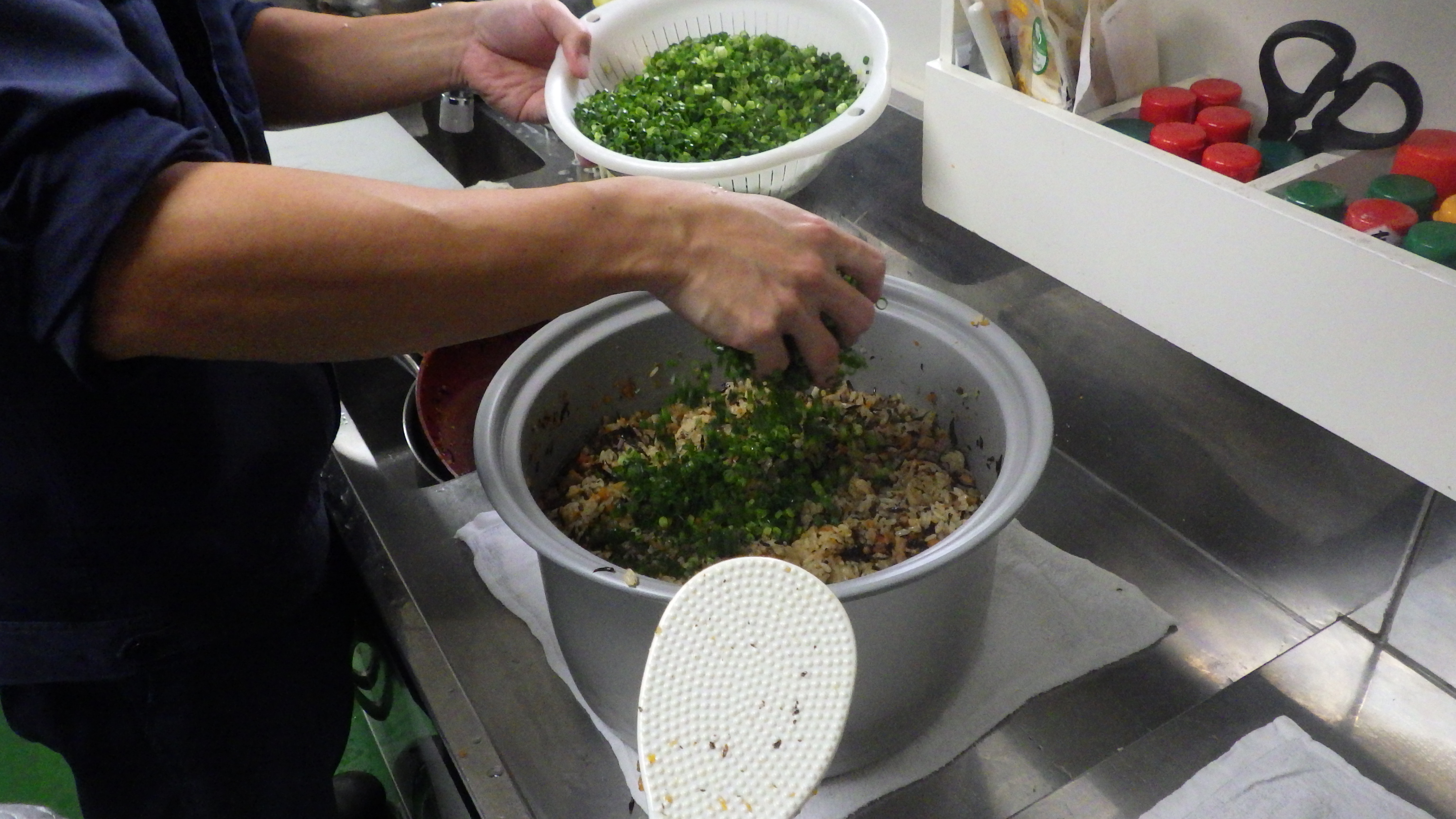 具材を混ぜた米に青ネギを入れる様子