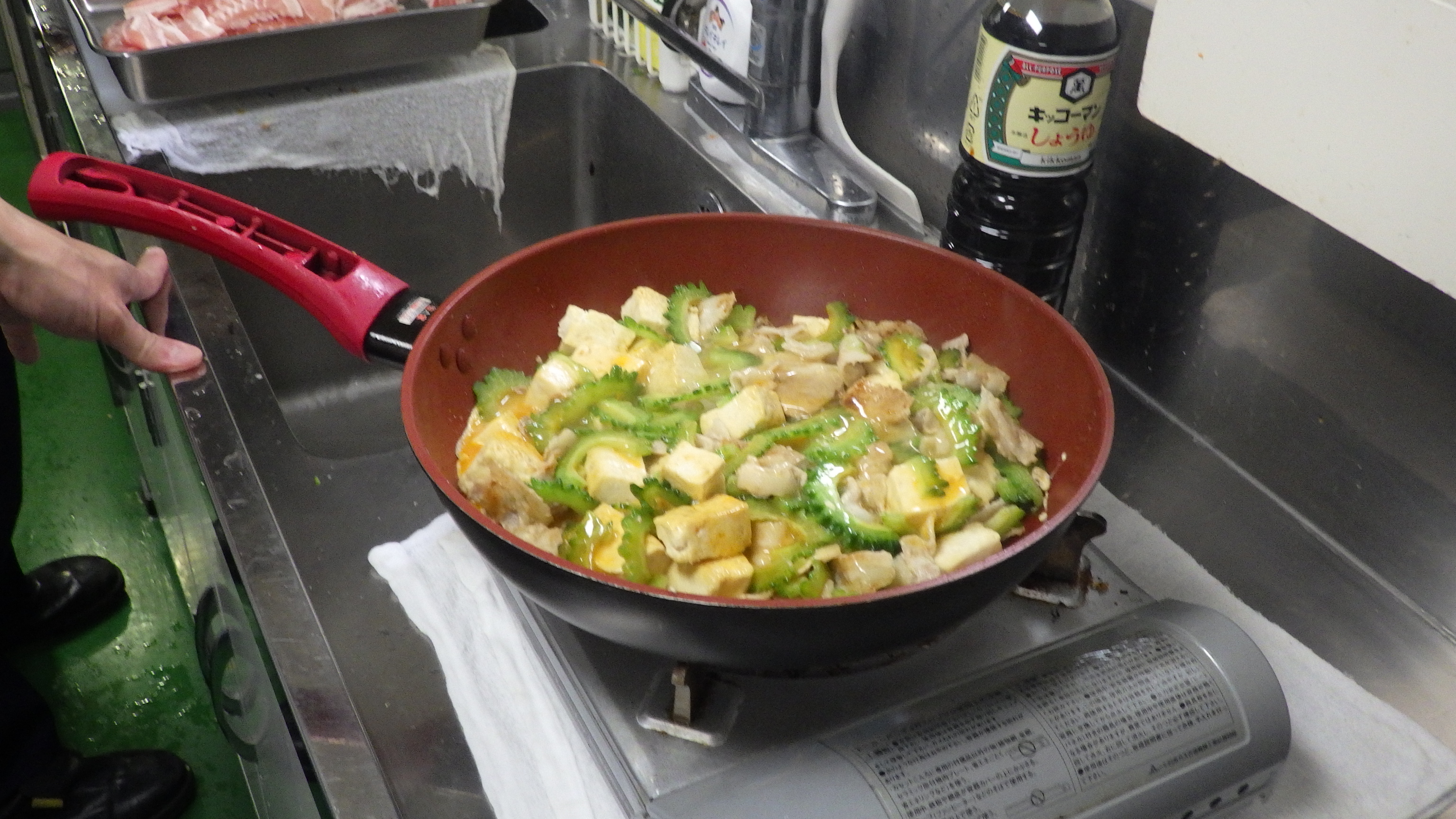 豆腐と豚バラとゴーヤを混ぜ炒める様子