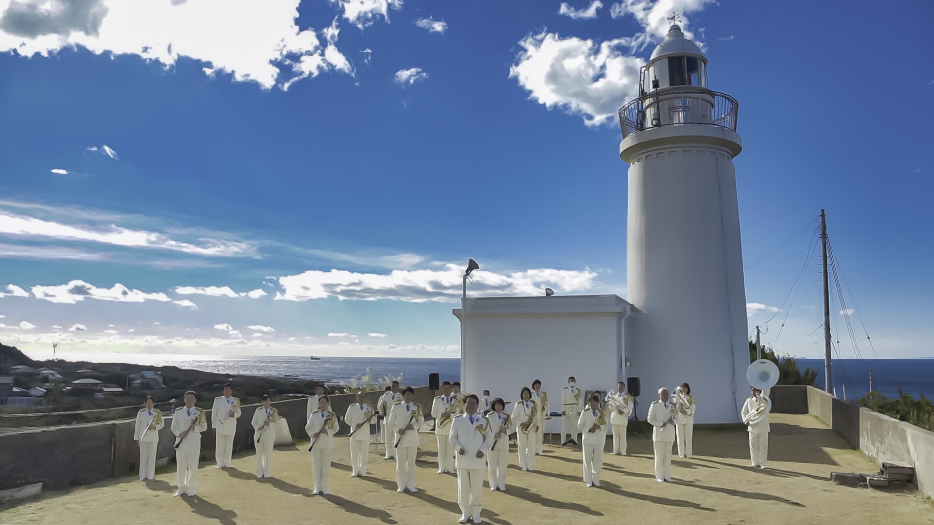 海上保安庁音楽隊が灯台の前に整列している写真