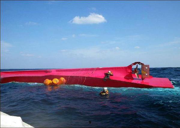 転覆船の船底をたたき生存者を捜す潜水士