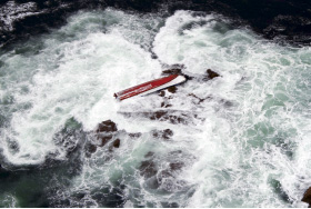 転覆漁船が岩場に乗り上げた状況